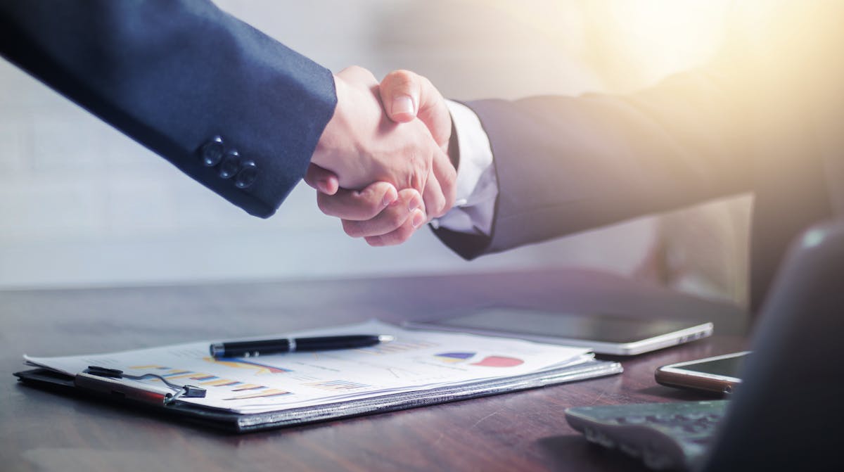 Business professionals shaking hands across a conference table after a successful salary negotiation meeting
